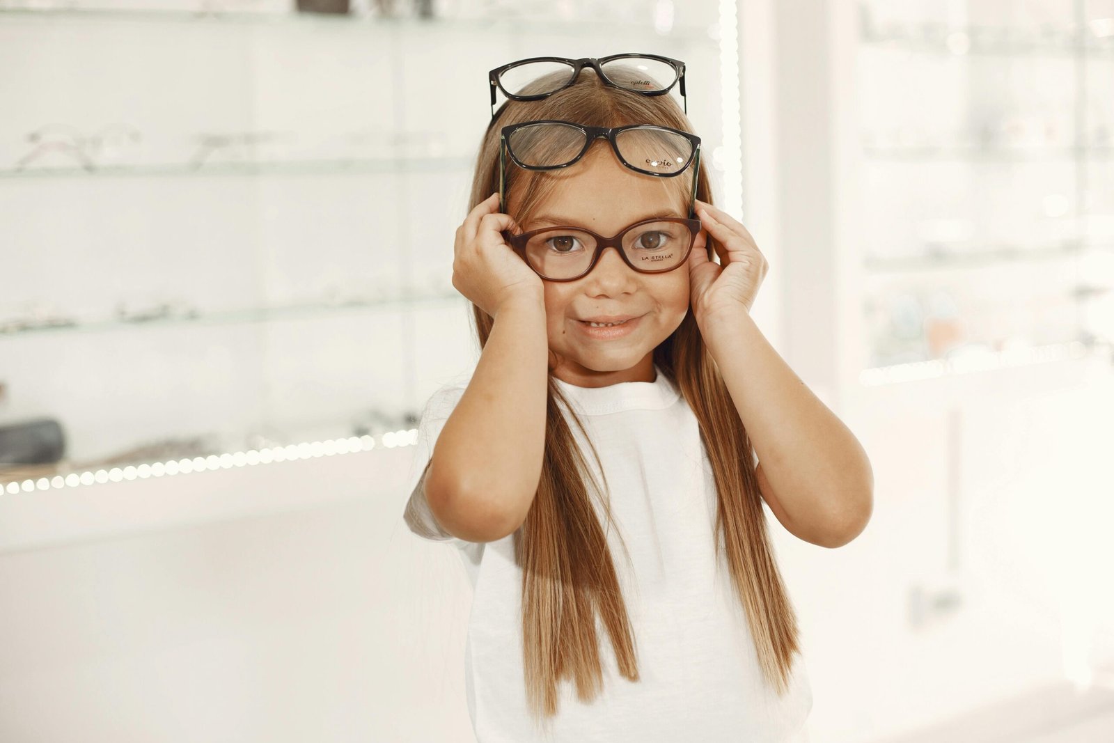 Cheerful girl trying on glasses in an optical shop, showcasing a fun eyewear selection process.